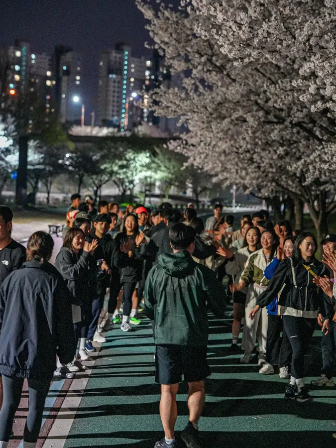 벚꽃 아래에서 회원들이 하이파이브하며 응원하는 장면
