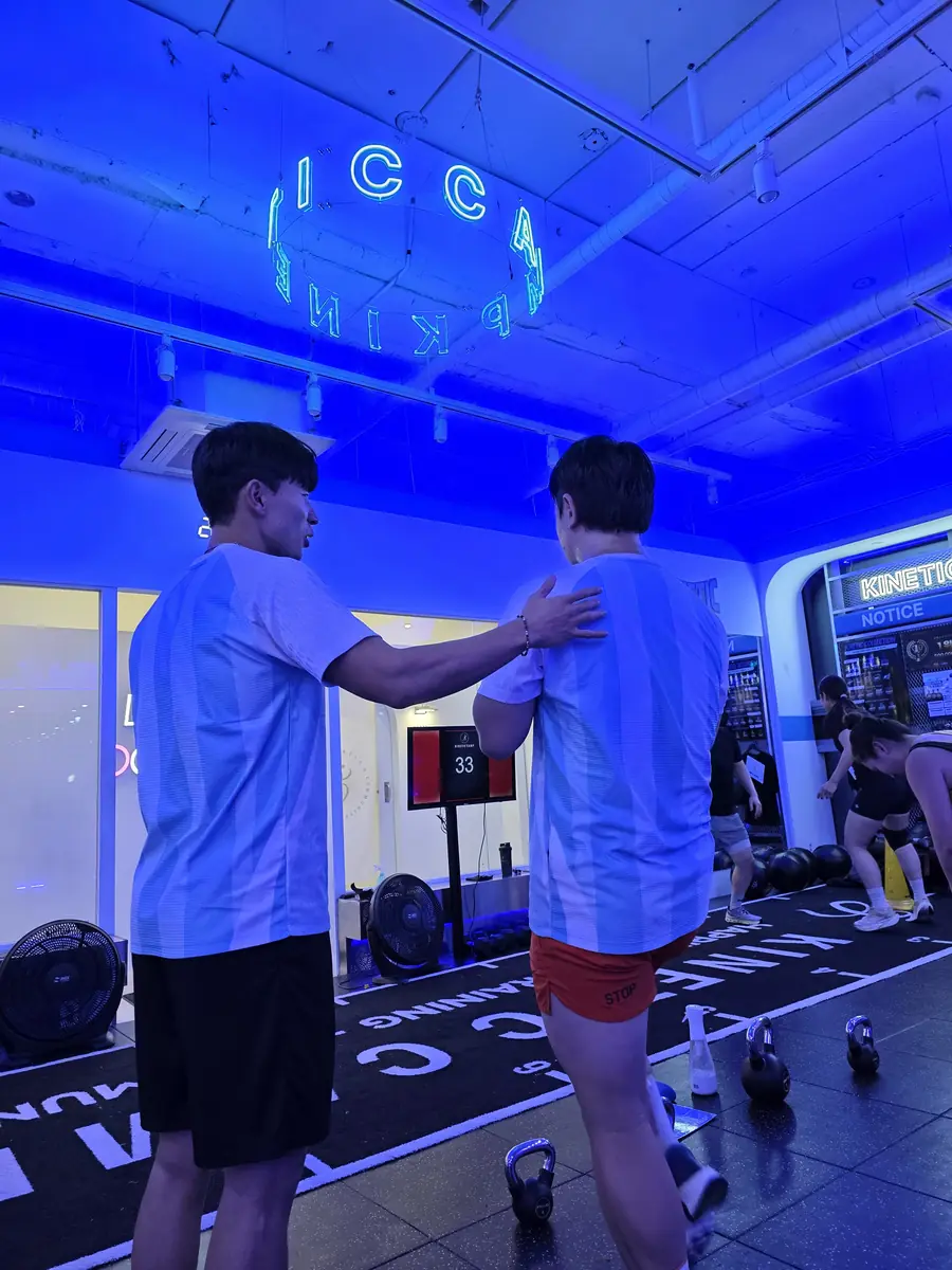 코치가 회원 옆에서 자세를 잡아 주는 장면